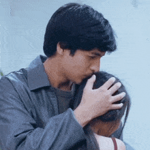 a man kisses a woman on the forehead while she looks on