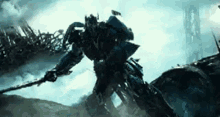 a transformer is holding a sword in his hand while standing on top of a rock .