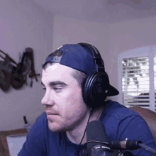 a man wearing headphones and a baseball cap looks to his left