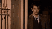 a man in a suit and tie is standing in a doorway .