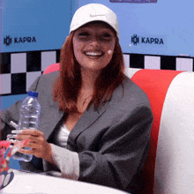 a woman wearing a white nike hat sits in a diner booth holding a water bottle