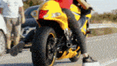 a woman riding a yellow motorcycle with a red shirt on