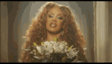 a woman with long red hair is holding a bouquet of white flowers .