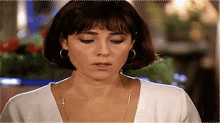 a woman wearing a white shirt and hoop earrings looks down