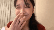 a close up of a woman covering her mouth with her hands .
