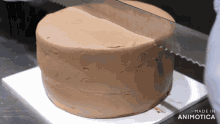 a chocolate cake is being sliced by a knife with the words made in animotica visible