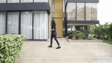 a woman walking in front of a house with the words made in animatica below her
