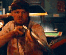 a man in a bandana is holding a knife in a dark room