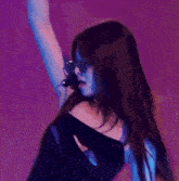 a woman wearing sunglasses and a microphone is standing in front of a blue background .