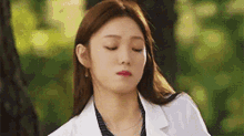 a close up of a woman wearing a white coat and a striped shirt .
