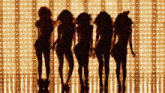 a group of women dancing in front of a wall of lights