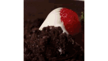 a person is putting a strawberry in a bowl of chocolate sauce .