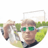 a man wearing sunglasses is holding a bottle of liquid