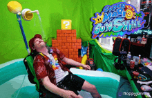 a man is laying in a pool with a super mario sunshine sign behind him