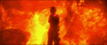 a silhouette of a man standing in front of a large fire