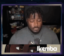 a man with his eyes closed is behind a sign that says ikemba
