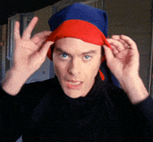 a man wearing a blue and red hat is making a peace sign with his hands