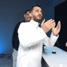 a man in a white shirt is clapping his hands in a blurry photo