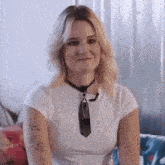 a woman wearing a white shirt and tie is sitting on a couch .