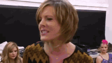 a woman with short hair is making a funny face while standing in front of a group of women .