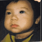 a close up of a baby 's face with a yellow shirt