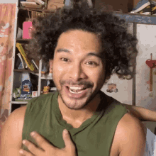 a man with curly hair is wearing a green tank top and smiling .