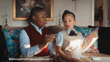 a boy and a girl are sitting on a couch with nbc written on the bottom