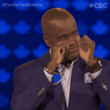 a man in a blue suit wipes his nose with his hands while standing in front of a cbs logo