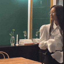 a woman in a white shirt is standing in front of a table with books on it