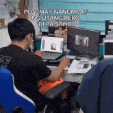 a man is sitting at a desk with two computer monitors and a laptop ..