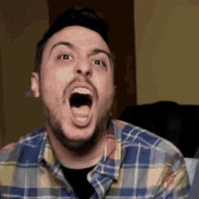 a man in a plaid shirt is making a funny face with his mouth open