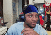 a man wearing headphones and a blue headband has a picture of a man in a mlb jersey behind him