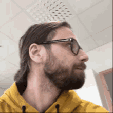 a man with a beard wearing glasses and a yellow sweatshirt