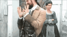 a man with a beard is standing in front of a woman in a dress .
