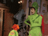 a woman in a green costume is standing next to a muppet in a green costume