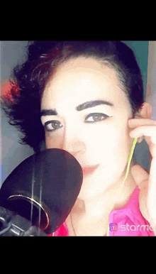 a close up of a woman 's face in front of a microphone with the word starm on the bottom right corner