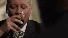 a man in a suit drinking a glass of wine