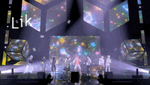 a group of people dancing on a stage with the word like on the screen