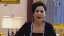 a woman in a black dress is sitting in a living room with a lamp and a sign that says ' 7 ' on it