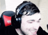 a man wearing headphones is sitting in a chair with a red pillow that says gto
