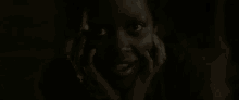 a close up of a child 's face in the dark with his hands on his face .