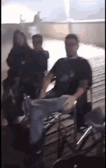 a man in a black shirt is sitting in a chair on a wooden deck .