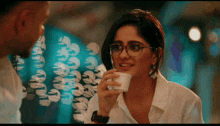 a woman wearing glasses is drinking from a small cup
