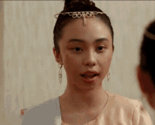 a woman wearing a tiara and earrings is making a face .