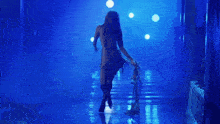 a woman is walking down a hallway with a blue light behind her