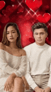 a man and a woman are sitting next to each other in front of a red background with hearts