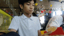 a young boy in a white shirt holds a red object