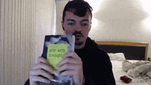 a man is holding a book called blindsight by peter watts