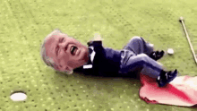a man is laying on the ground on a golf course with his head on a golf ball .