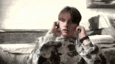 a young man is sitting on a couch listening to music with headphones on .